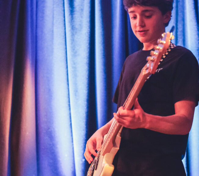 A male student plays an electric guitar on stage