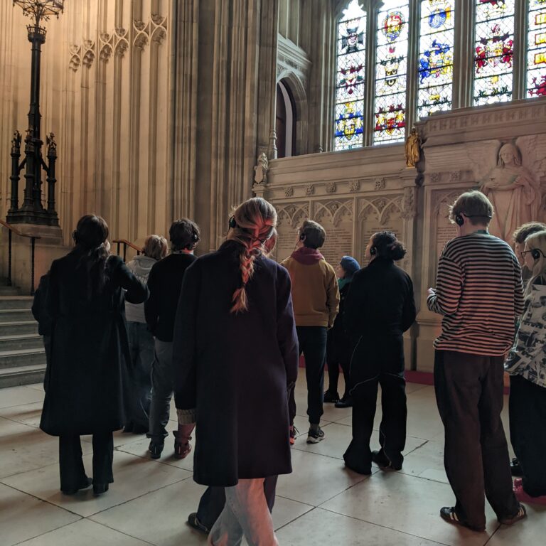 A group of students admire the internal architecture of the Houses of Parliament, including a grand stained glass window