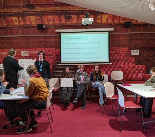 A group of Sixth Form students are seen working together to create fictional political policies in the Houses of Parliament