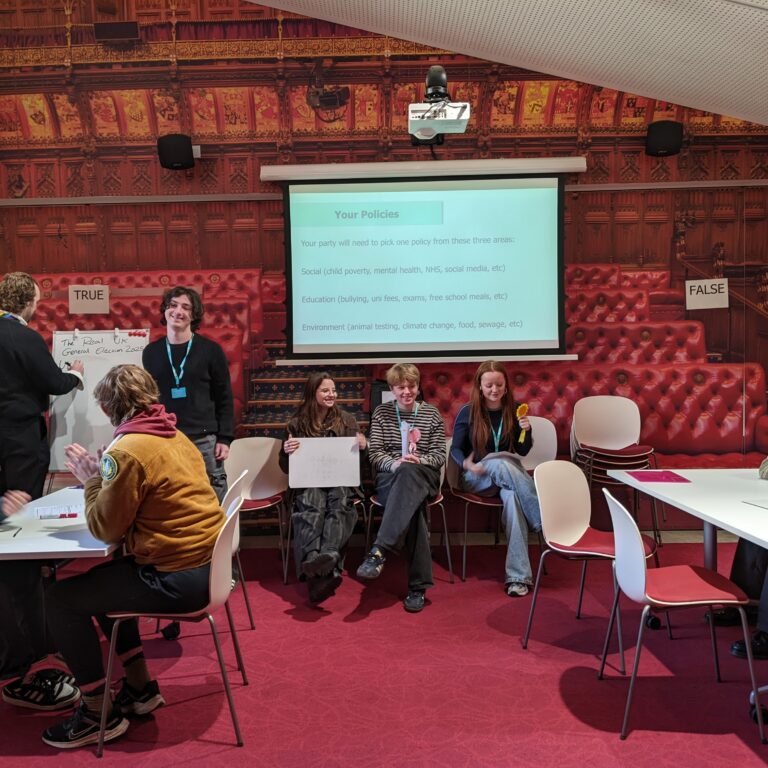 A group of Sixth Form students are seen working together to create fictional political policies in the Houses of Parliament