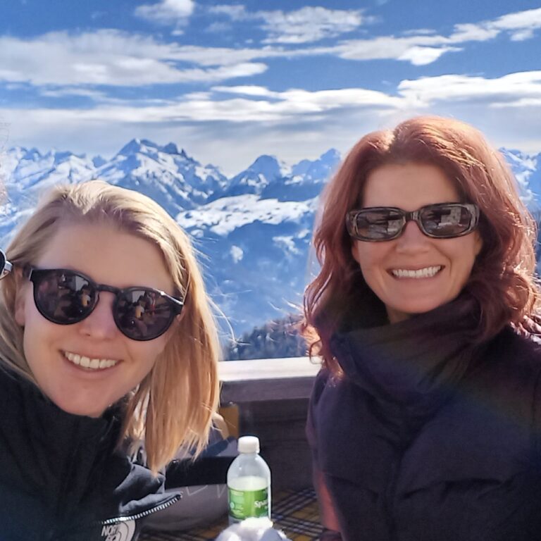 Four teachers from The King Alfred School smile in front of a beautiful snowy mountain scene