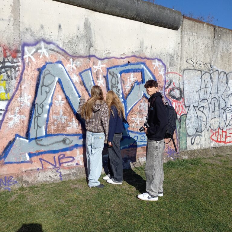 Two students look at a graffitied section of the Berlin Wall
