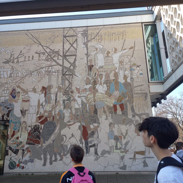 Two male students look at a section of old decorated wall in Berlin