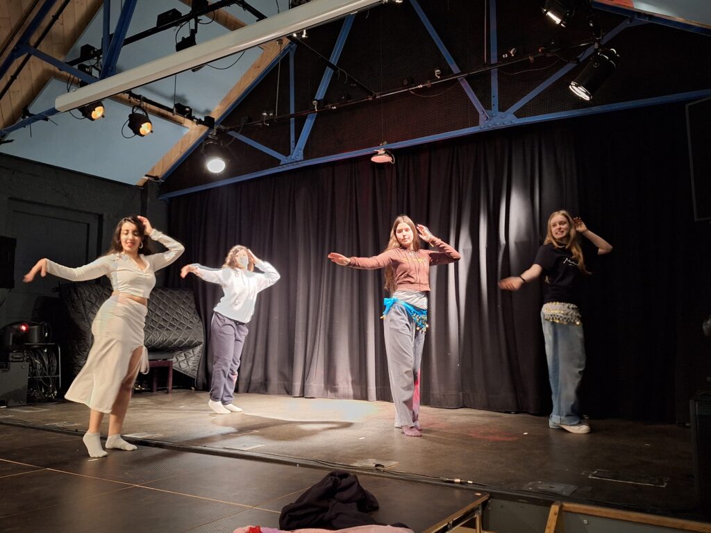 Female student perform bellydancing moves on a stage