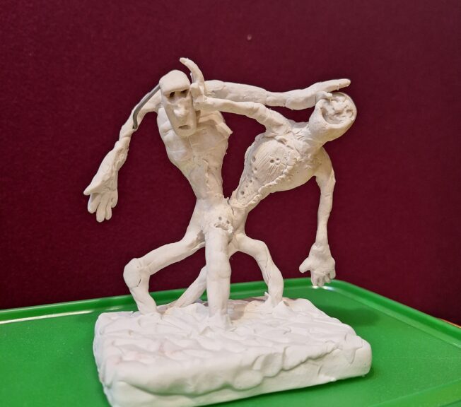 A sculpture showing two figures tussling with one another. One is happy, the other looks scared. It is an artistic representation of society's mixed feeling towards AI technology.