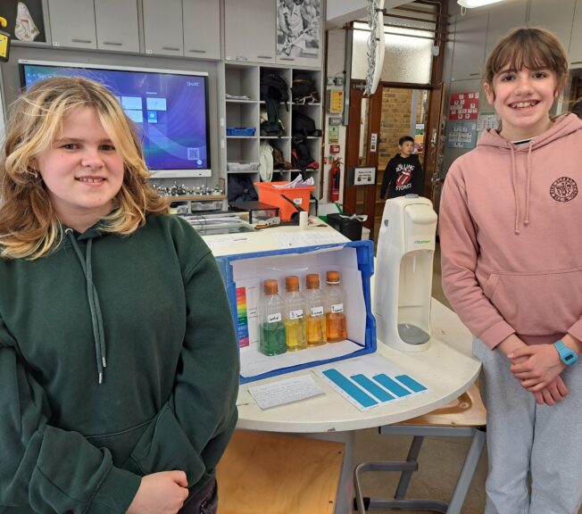 Two students pose next to technical equipment in a science lab, ready to explore how CO2 affects our oceans