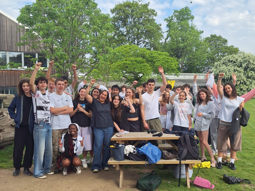 A group of Year 11 students from The King Alfred School pose with their Head of Year on a school field