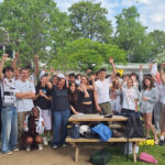 A group of Year 11 students from The King Alfred School pose with their Head of Year on a school field