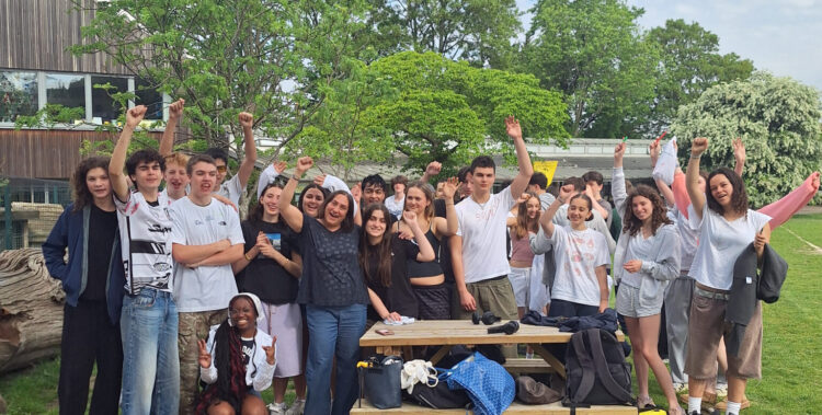 A group of Year 11 students from The King Alfred School pose with their Head of Year on a school field