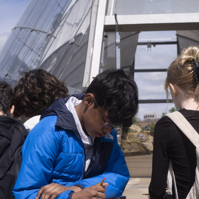 Students sit sketching outside a glasshouse at Kew Gardens