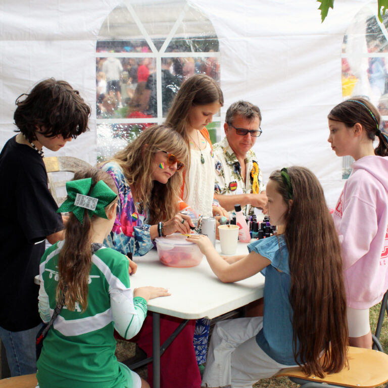 Children and adults paint nails at a stall at The King Alfred School's summer fair