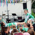 Student cheerleaders smile as the attempt an arial stunt in front of a large crowd