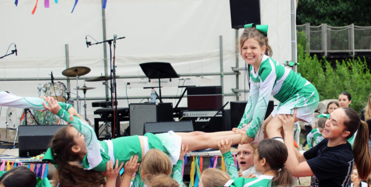 Student cheerleaders smile as the attempt an arial stunt in front of a large crowd