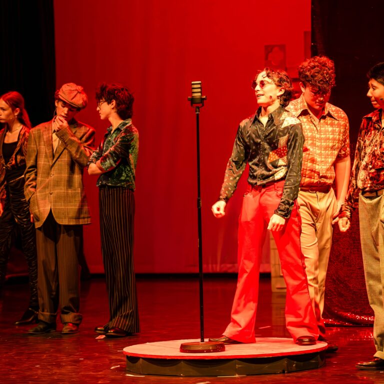 Male students on stage during a performance of Sister Act Jr