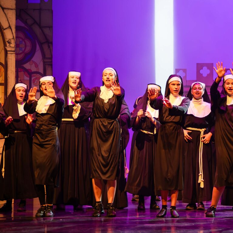 Female students dressed as nuns sing and dance on stage during The King Alfred School's production of Sister Act Jr
