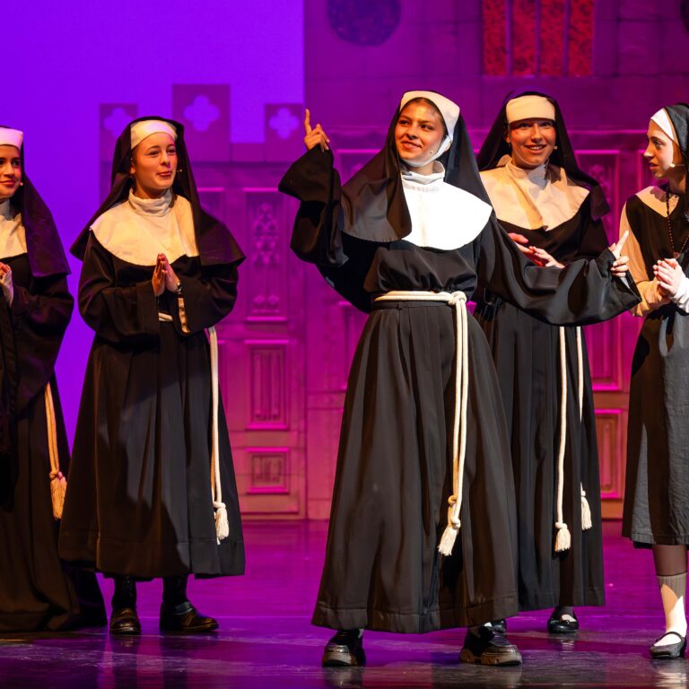 Students dressed as nuns perform on stage during Sister Act Jr