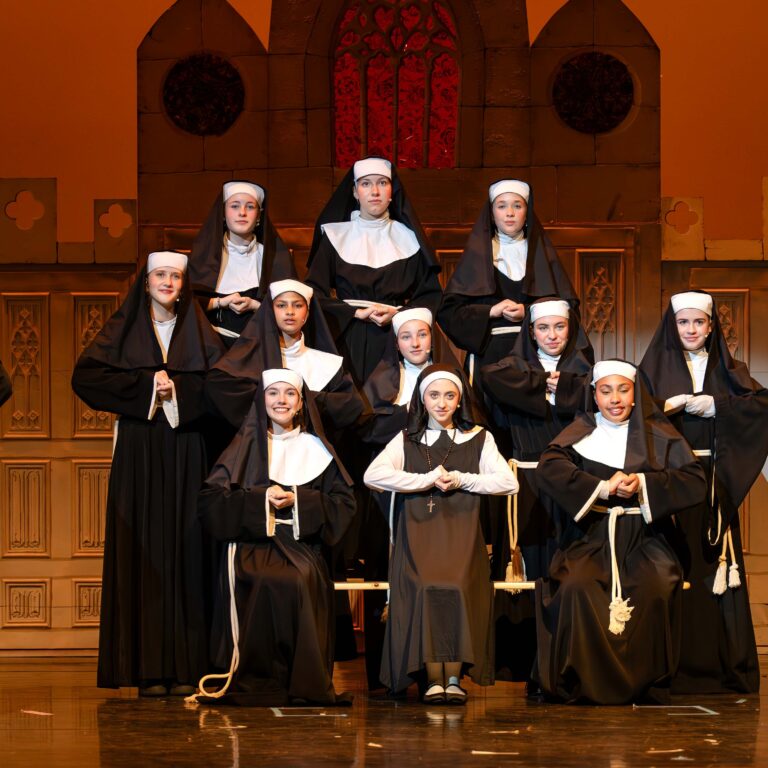 Students dressed as nuns perform on stage during Sister Act Jr