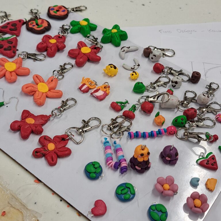 Close-up of brightly coloured student-made jewellery and phone charms, with designs including flowers, smiley faces and slices of watermelons