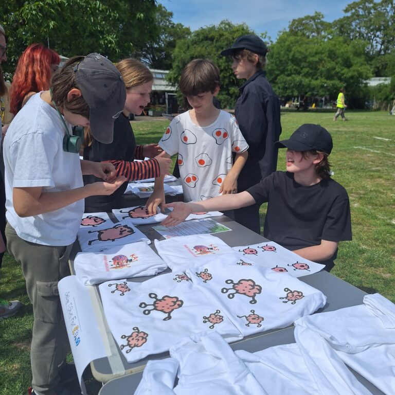 Male students man a t-shirt stall at The King Alfred School, North London