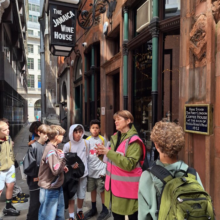 Students from The King Alfred School listen to a tour guide outside of The Jamaica Wine House in The City of London