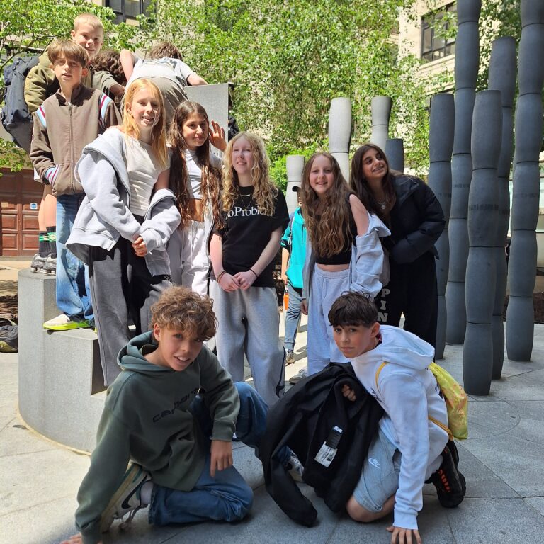 A group of students stand next to the a sculpture in The City of London
