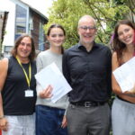 Three female students hold the GCSE exam results alongside a male and female teacher at The King Alfred School