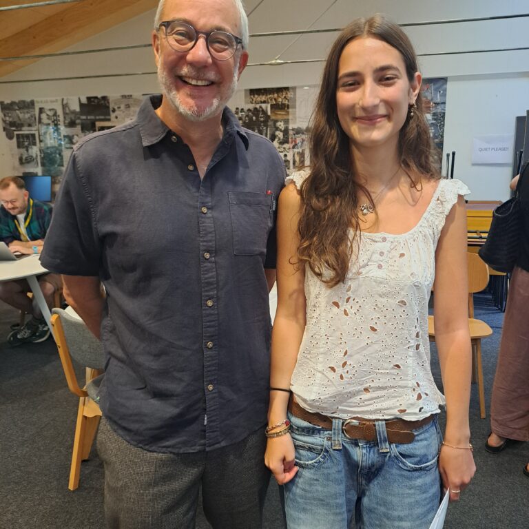 A female student stands next to her male head teacher. They are in the Sixth Form study area of The King Alfred School.