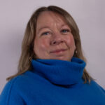 Headshot of a woman in a blue rollneck jumper