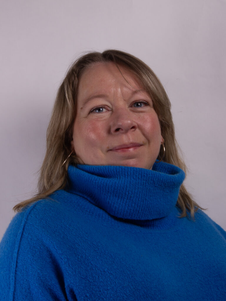 Headshot of a woman in a blue rollneck jumper