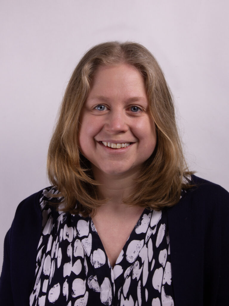 Headshot of a woman with mid length blonde hair wearing a black and white top