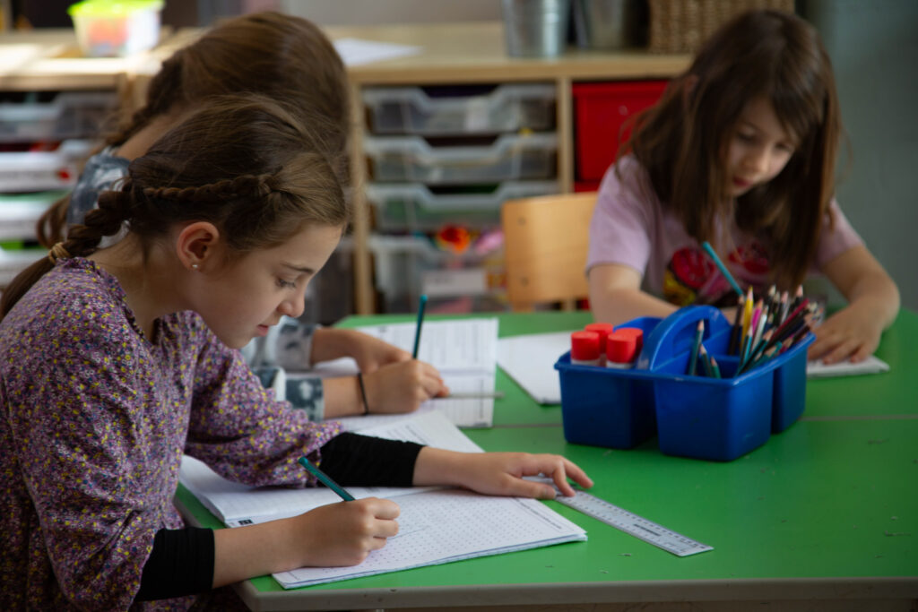three children work at a green table