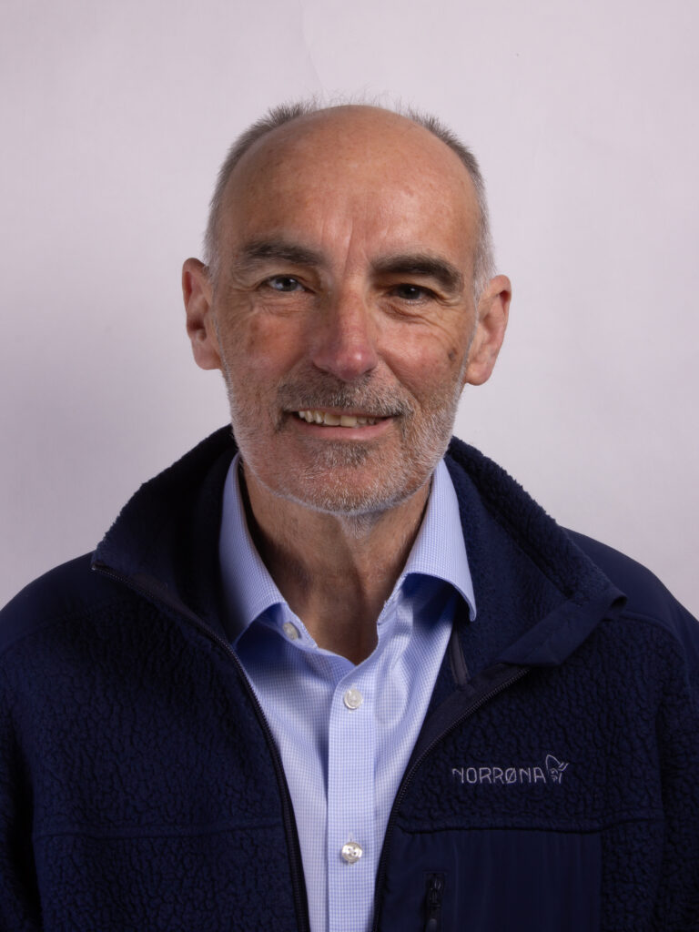 Headshot of a man with a short beard and wearing a blue shirt and blue jacket