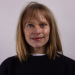 Headshot of a woman with mid length hair wearing a dark sweater