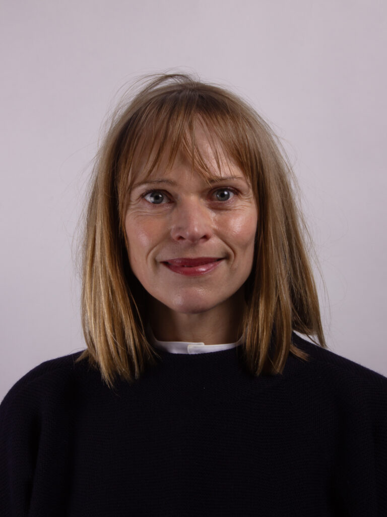 Headshot of a woman with mid length hair wearing a dark sweater