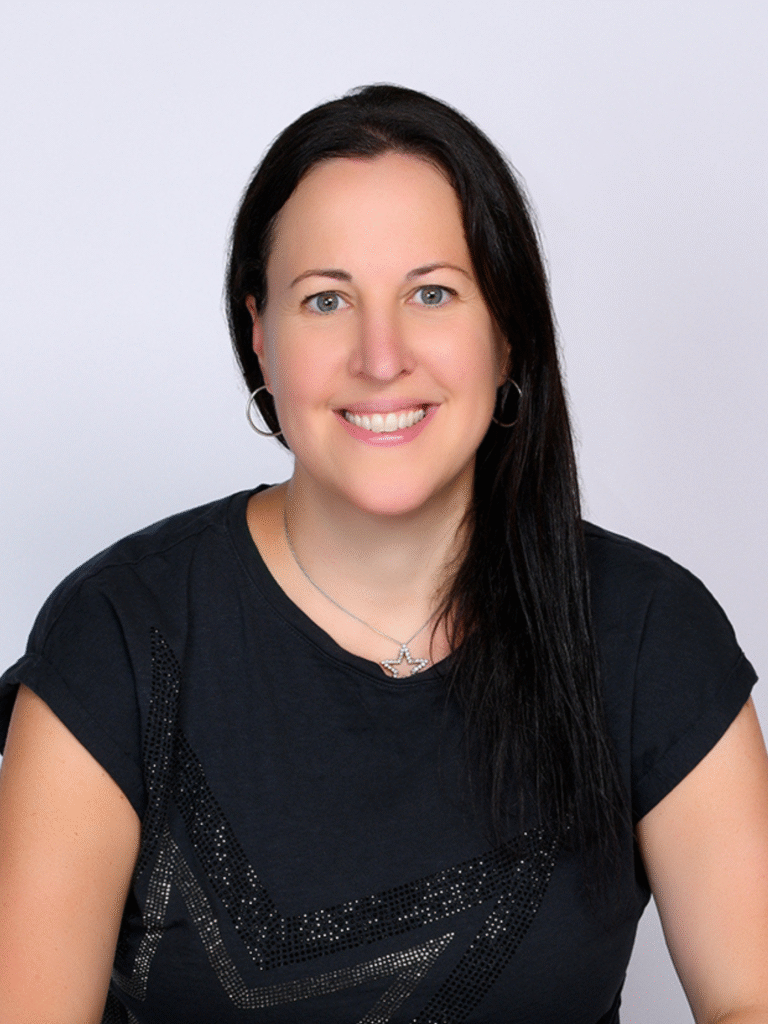 Headshot of a woman with long dark hair pulled to one side wearing a black tshirt with sparkles on