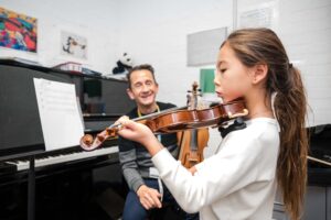 a teacher instructs a student who is playing the violin