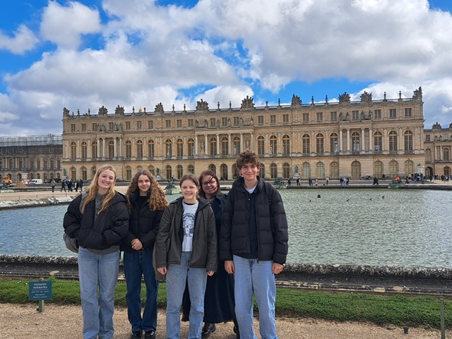 a group of four students and a teacher from The King Alfred School standing in front of The Palace of Versaille