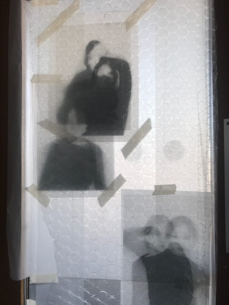 photographs seen behind bubble wrap creating fuzzy silhouettes