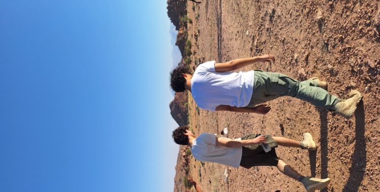 Four older students and smaller boy pictured from behind, walking through the Namibian desert